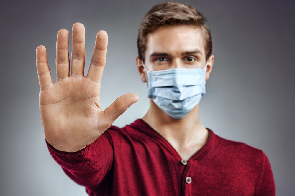 Man wearing face mask with hand out in front